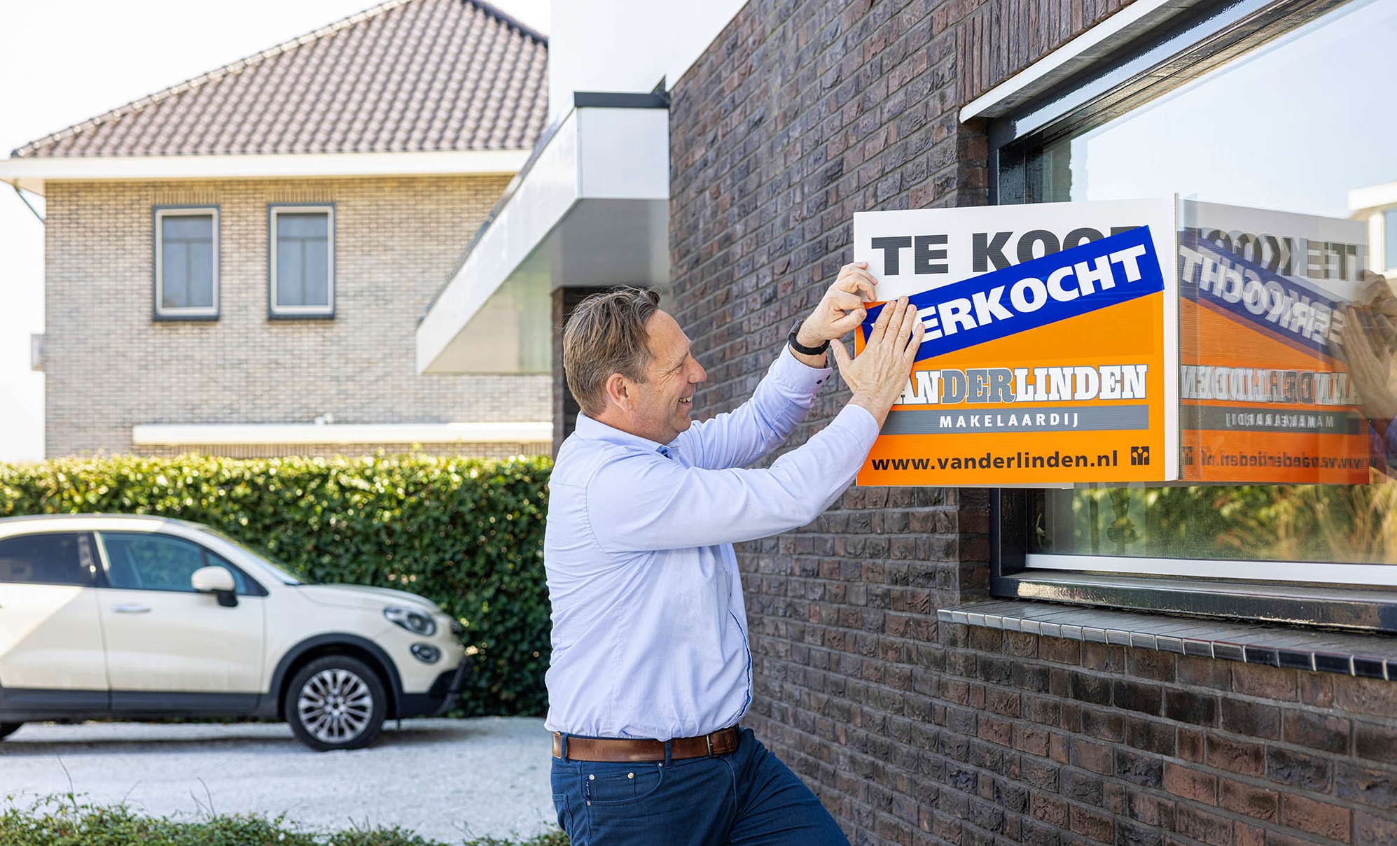 Real estate agent puts a sold sticker on a house that has just been sold