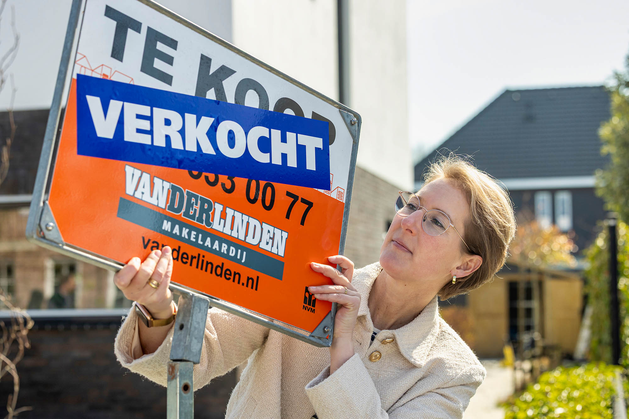 Realtor putting sold sticker on for sale sign